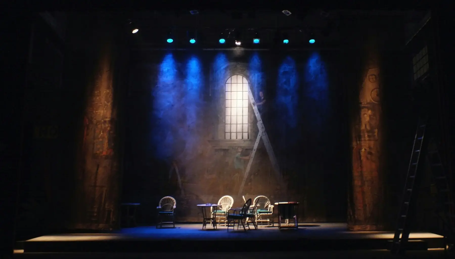 Un escenari a les fosques travessat per focus de llum blava.